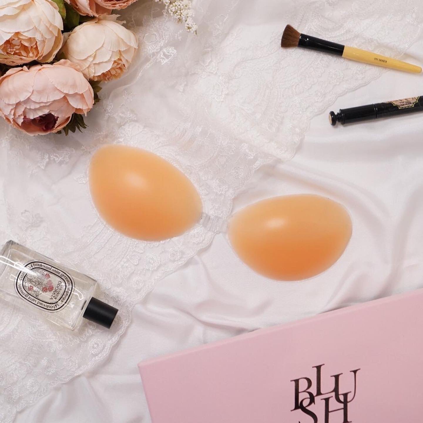 婚紗配件場景:膚色半月形 Nubra 置於蕾絲與絲緞上,搭配花束、粉色包裝盒與化妝用品